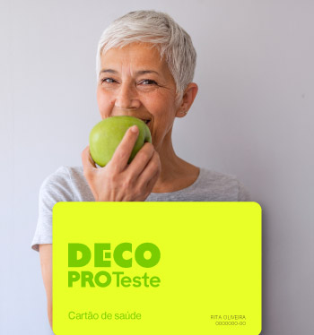 Mulher sorridente a comer uma maçã e com o cartão teste saúde.